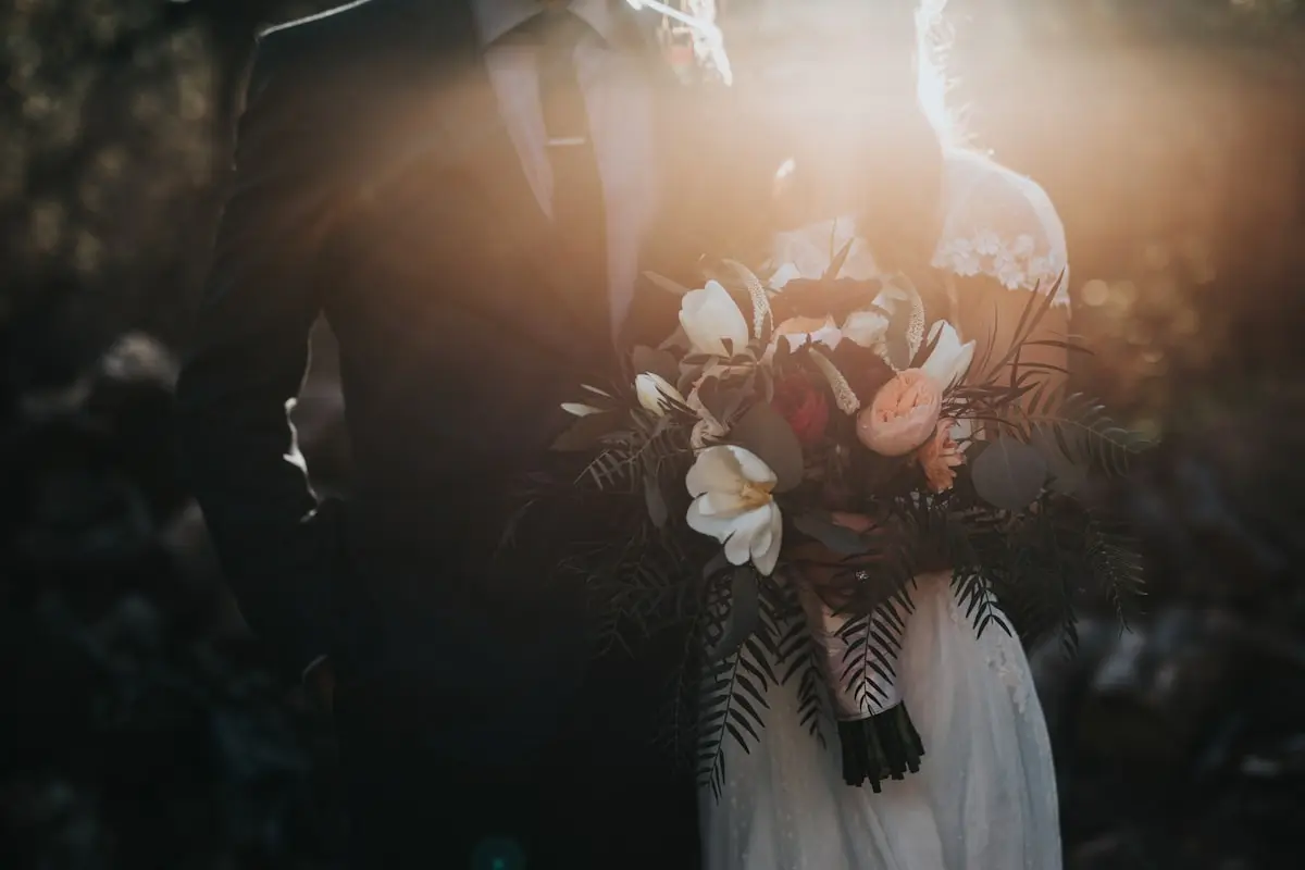 couple embracing in a warmly lit venue, surrounded by friends and family